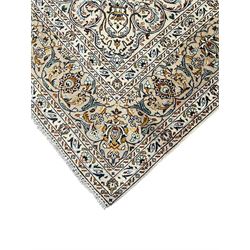 Persian Kashan ivory ground carpet, central pole medallion surrounded by swirling leafy branches and stylised plant motifs, scrolled foliate spandrels, the main border decorated with scrolling pattern and repeating palmettes, within floral patter guard stripes 