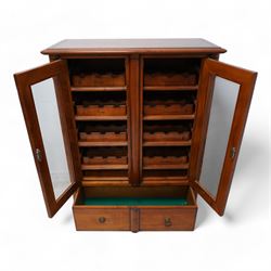 Cherrywood wine rack cabinet, moulded rectangular top over two glazed doors, fitted with eight slides each with three bottle holders inscribed with various wine types, single long drawer to the base 