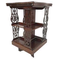 Edwardian mahogany revolving bookcase, the shaped moulded top inlaid with cusped panel and trailing bellflowers within a satinwood frame, foliate pierced upright splats and central square column supporting two tiers, on cruciform base with brass and ceramic castors 