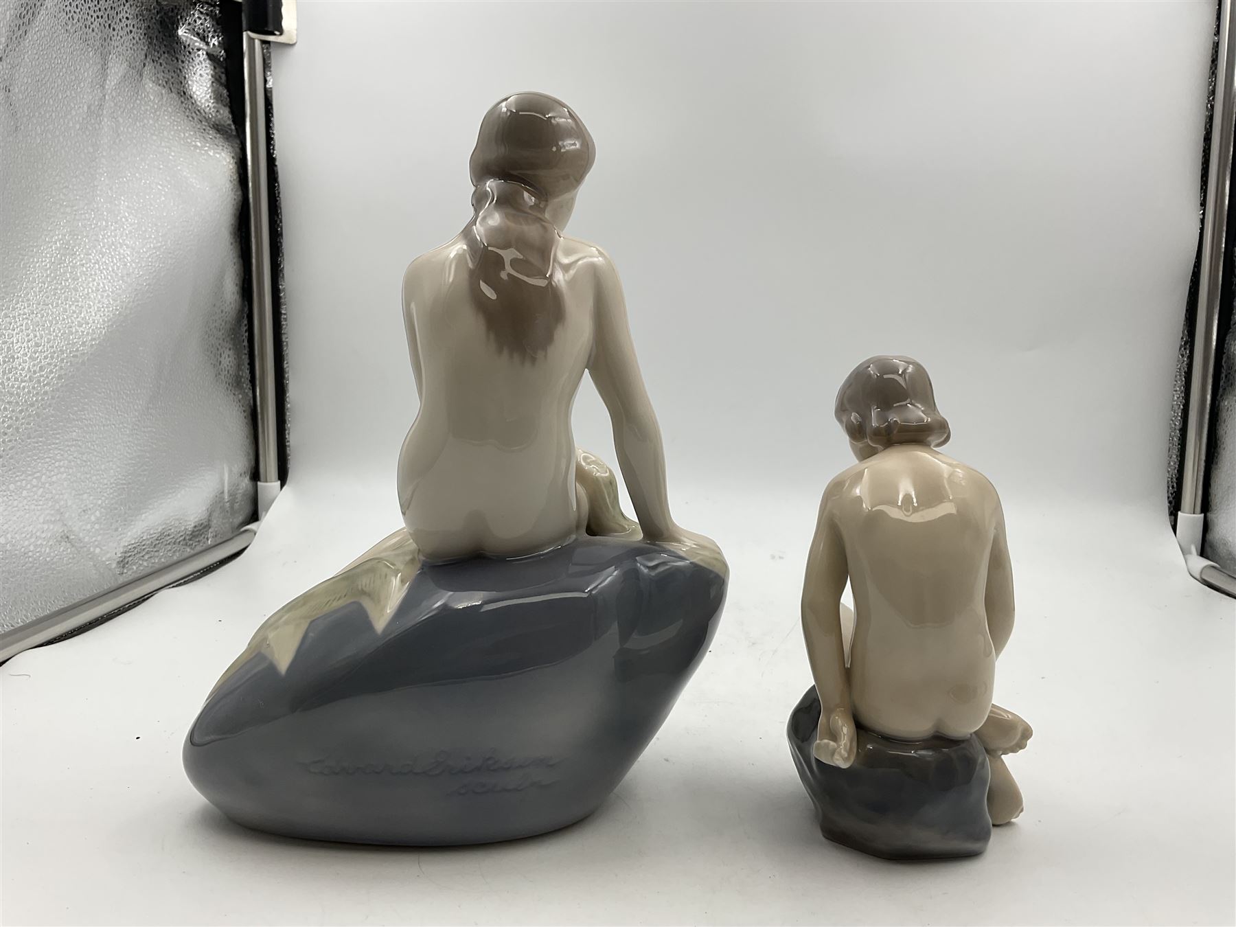 Two Royal Copenhagen figures, comprising The Little Mermaid, modelled by Edvard Eriksen, no. 4431 and Royal Copenhagen girl on stone no 4027, Little Mermaid H22cm