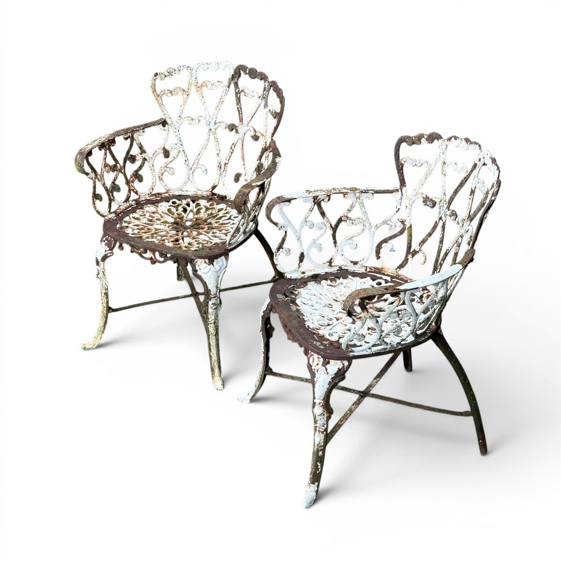 Pair of late 19th century painted cast iron garden chairs, open scroll and heart backs, ornate circular seat, raised on cabriole legs with X stretcher