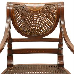 Pair of Sheraton Revival painted mahogany open armchairs, scrolled cresting rail with floral painted decoration over a double-caned back and rose-branch painted back bar, cane seat over C-scroll-painted seat rail, on splayed tapering supports, with all-over painted ebony faux stringing