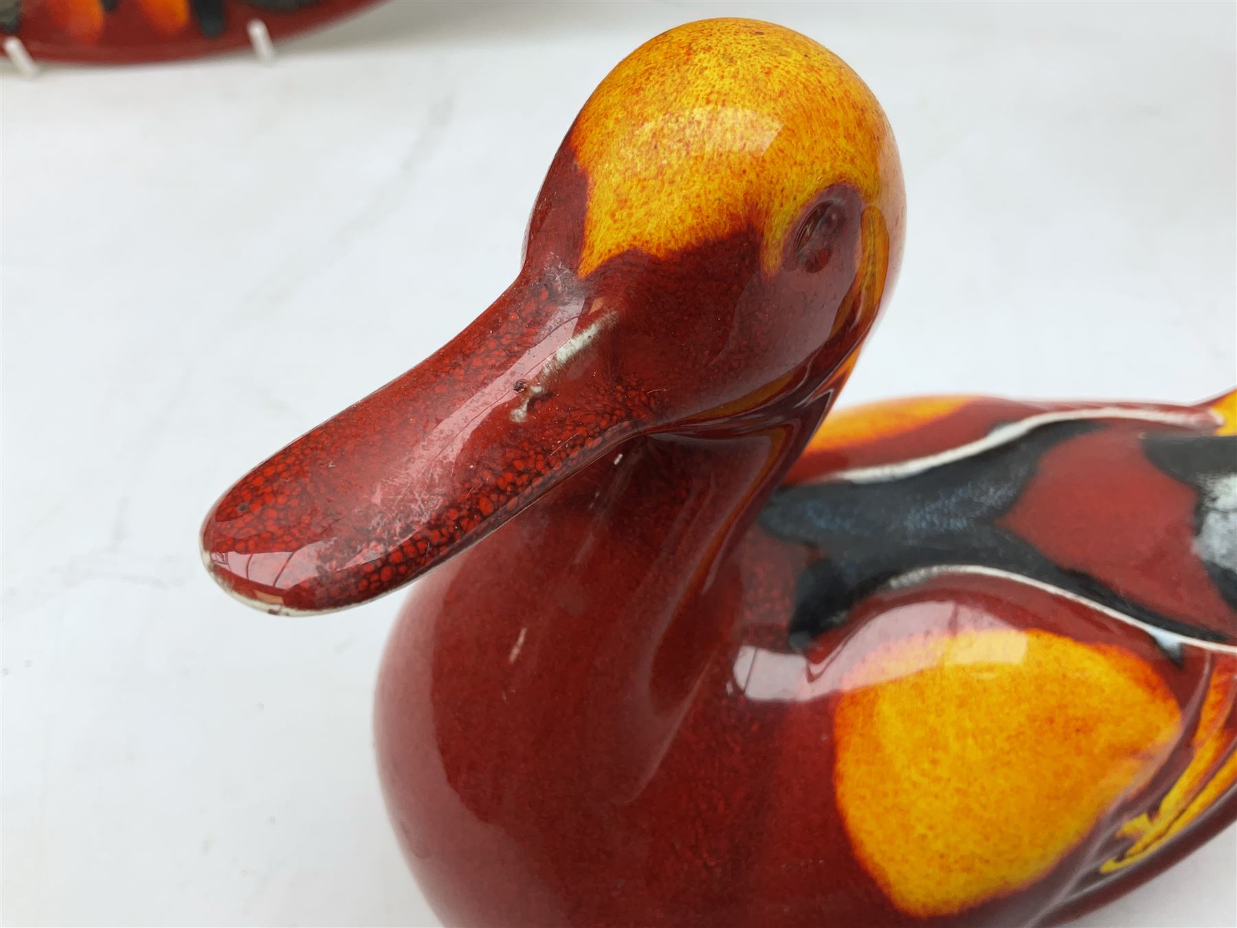 Collection of Poole Pottery, comprising charger and vase in Volcano pattern and a duck figure in a similar pattern 