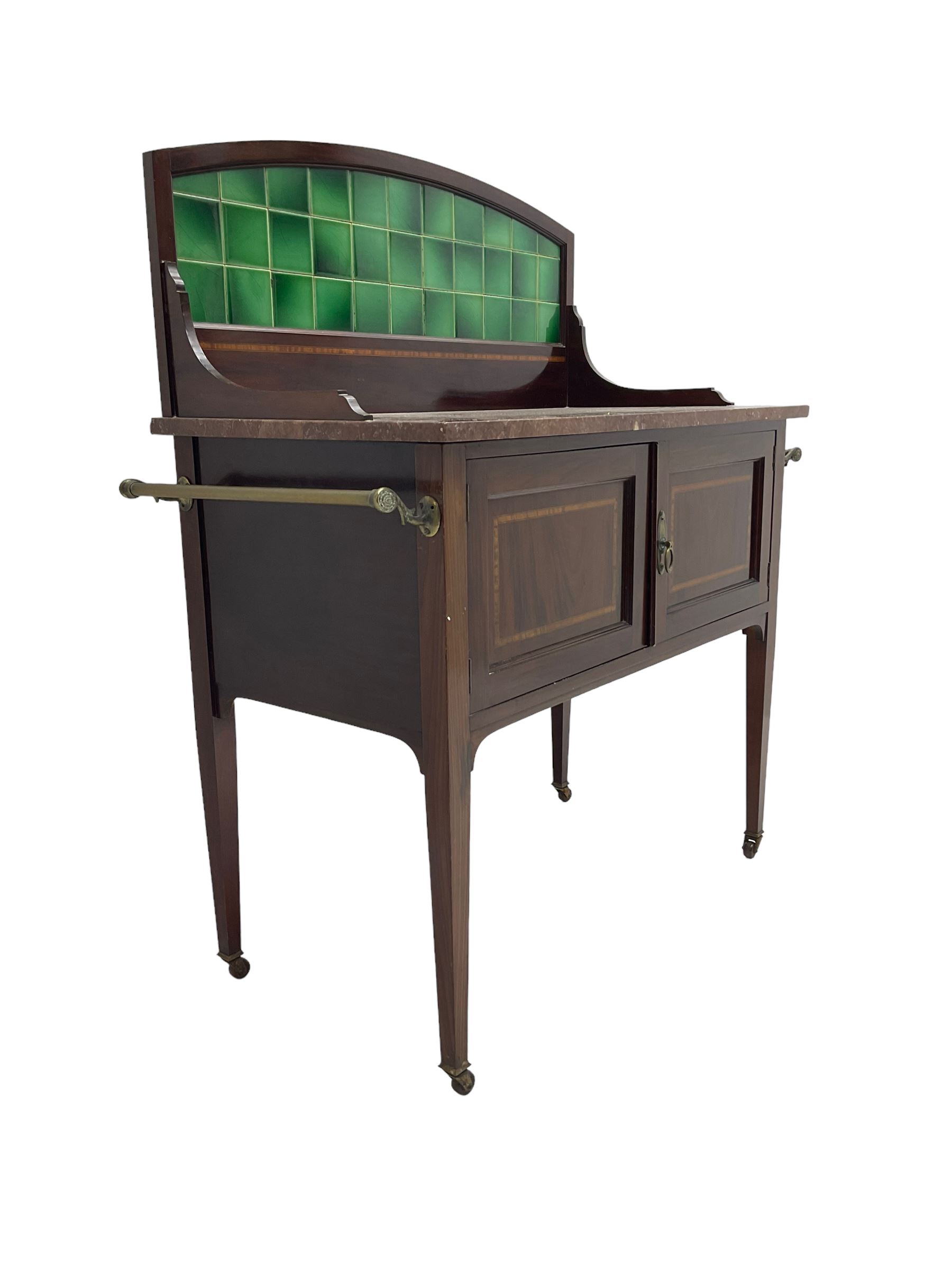 Edwardian inlaid mahogany washstand, raised back with emerald green tiles over marble top, fitted with two panelled cupboard doors, raised on square tapering supports on ceramic castors