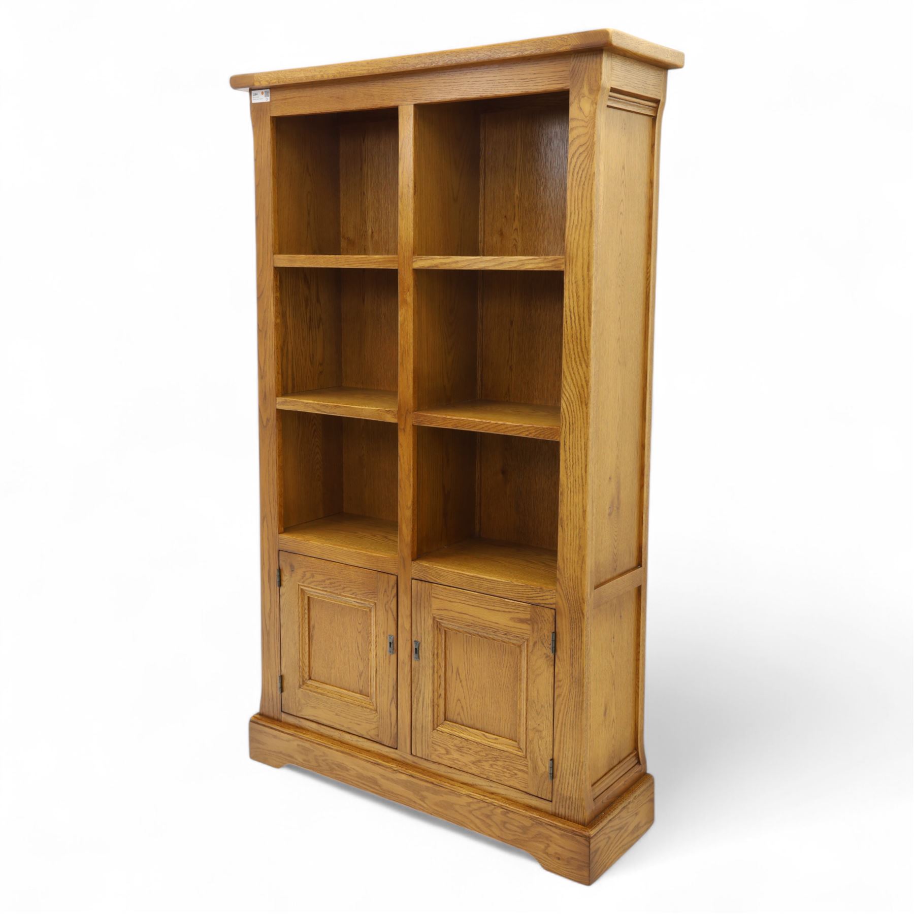 Old Charm - 'Chatsworth' light oak bookcase with two cupboards, featuring two fixed horizontal shelves forming six  rectangular open compartments, over twin panelled cupboard doors, chamfered uprights and plinth base