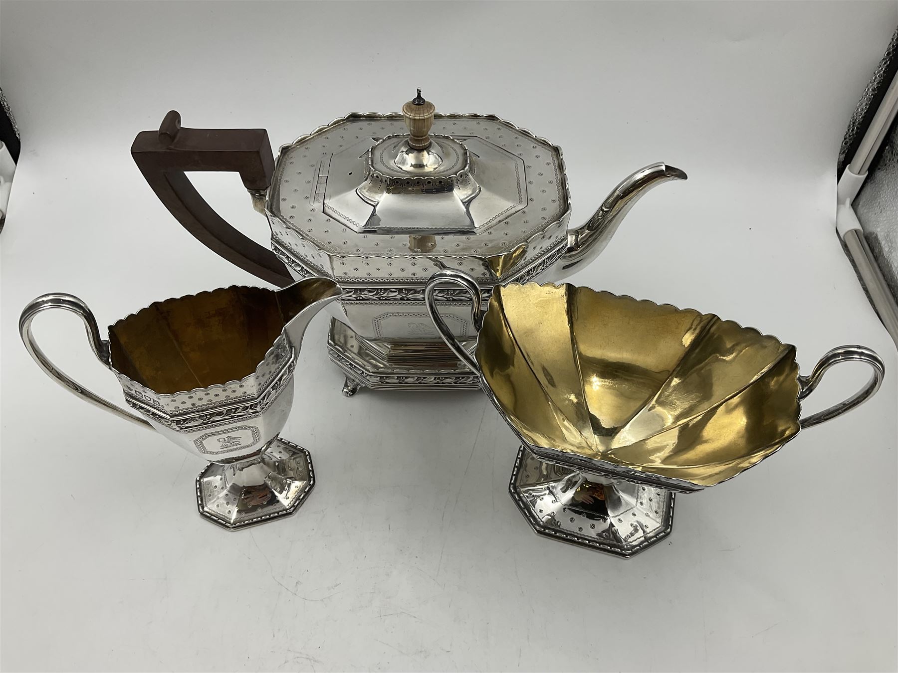 Victorian silver four piece tea service, comprising teapot, teapot stand, twin handled open sucrier and milk jug, each of octagonal form with foliate bud border and engraved decoration including crest to canted panels, and vacant panels, the teapot with ivory finial to the hinged cover and later wooden handle, hallmarked Edward Barnard & Sons Ltd, London1896, teapot including finial H15cm, milk jug including handle H16cm, teapot stand W11.5cm

This item has been registered for sale under Section 10 of the APHA Ivory Act