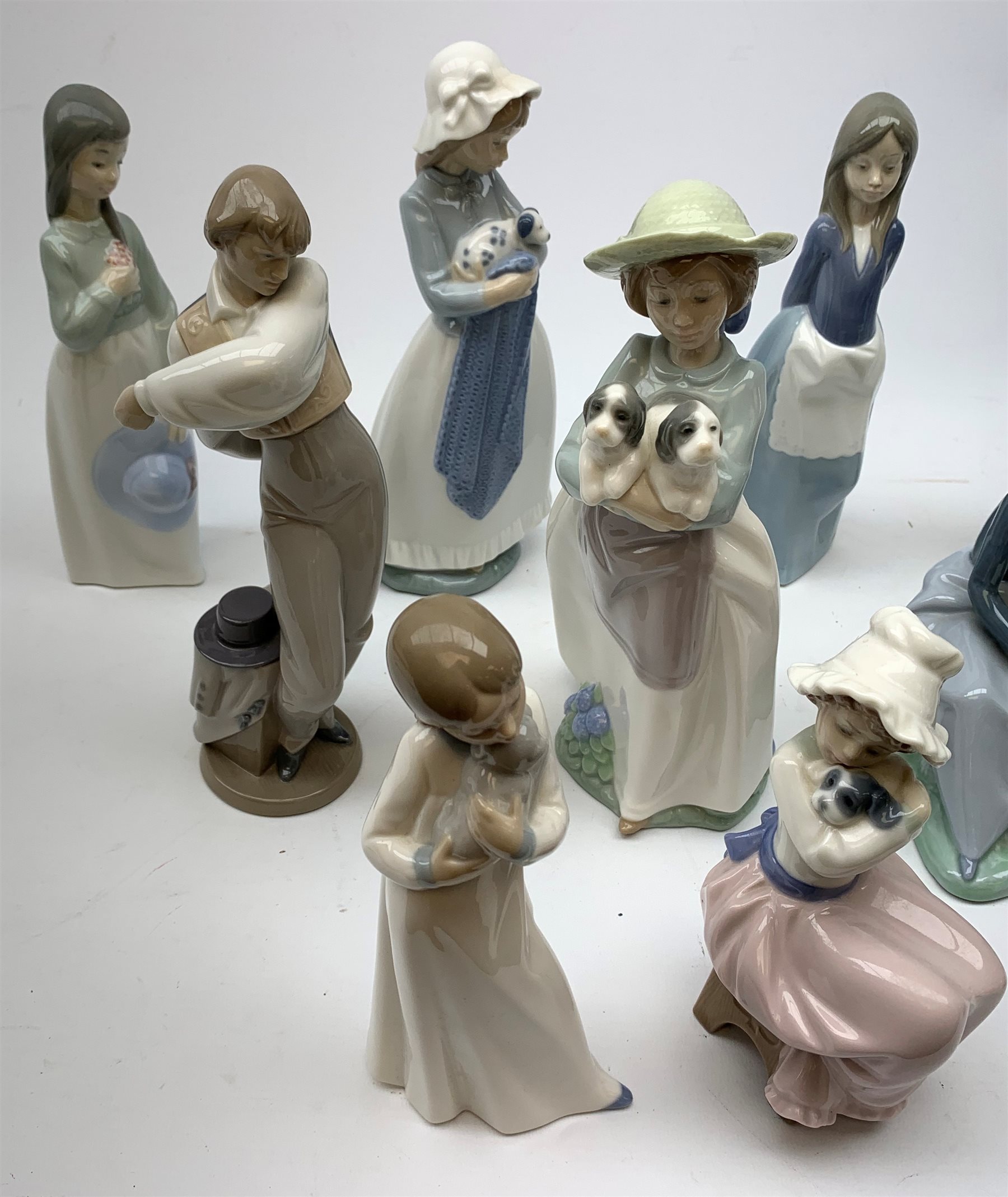 A group of thirteen Nao figurines, together with one Lladro figurine, each with printed mark beneath. 