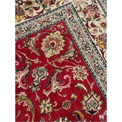 Persian Tabriz crimson ground carpet, decorated with swirling leafy branches and large palmette motifs, the pale ground border decorated with trailing foliate pattern, within floral guard stripes