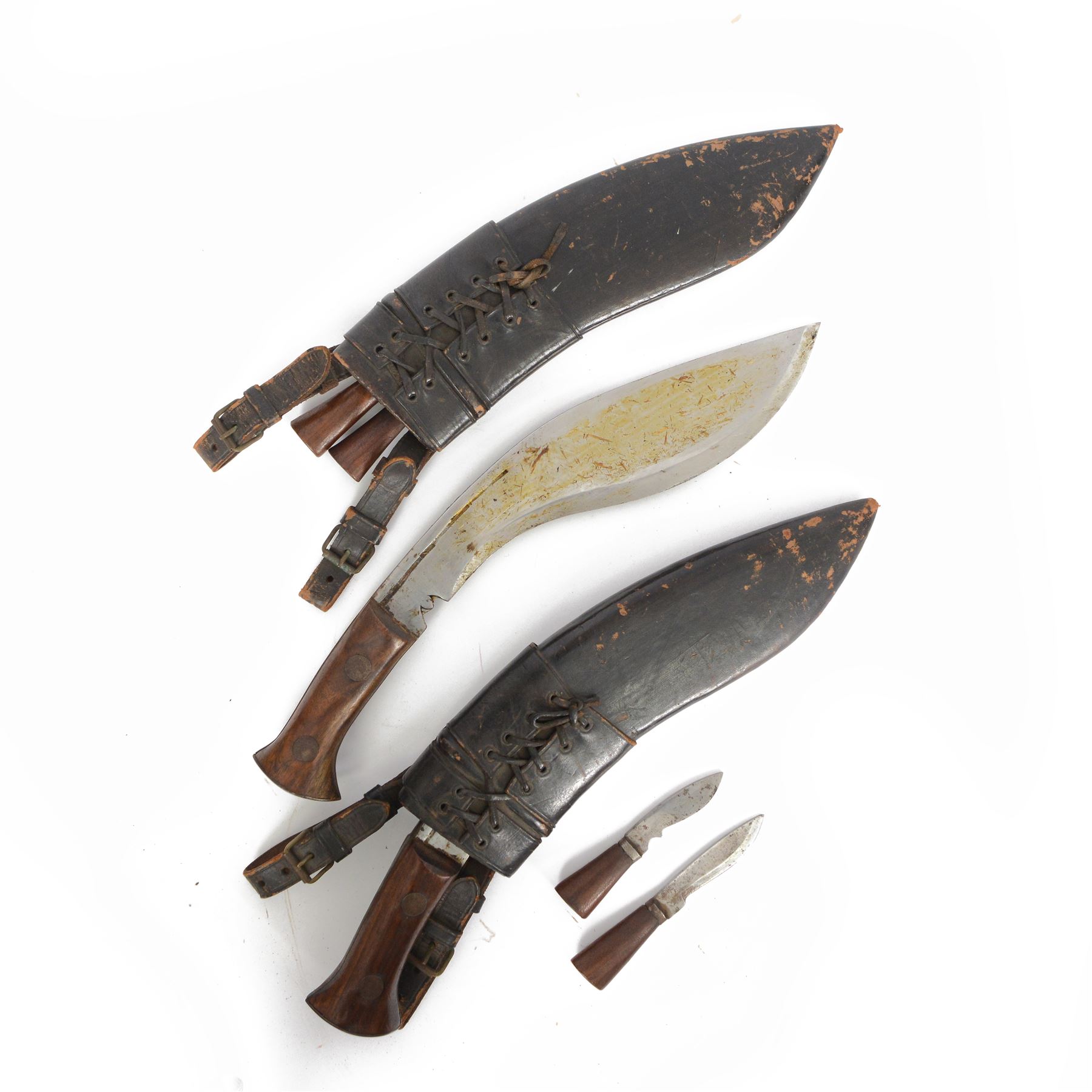 Two WWII Kukri knives, wooden grip with brass cap to pommel, single edged curved blade, within leather scabbard with belt attachments, overall L40cm 