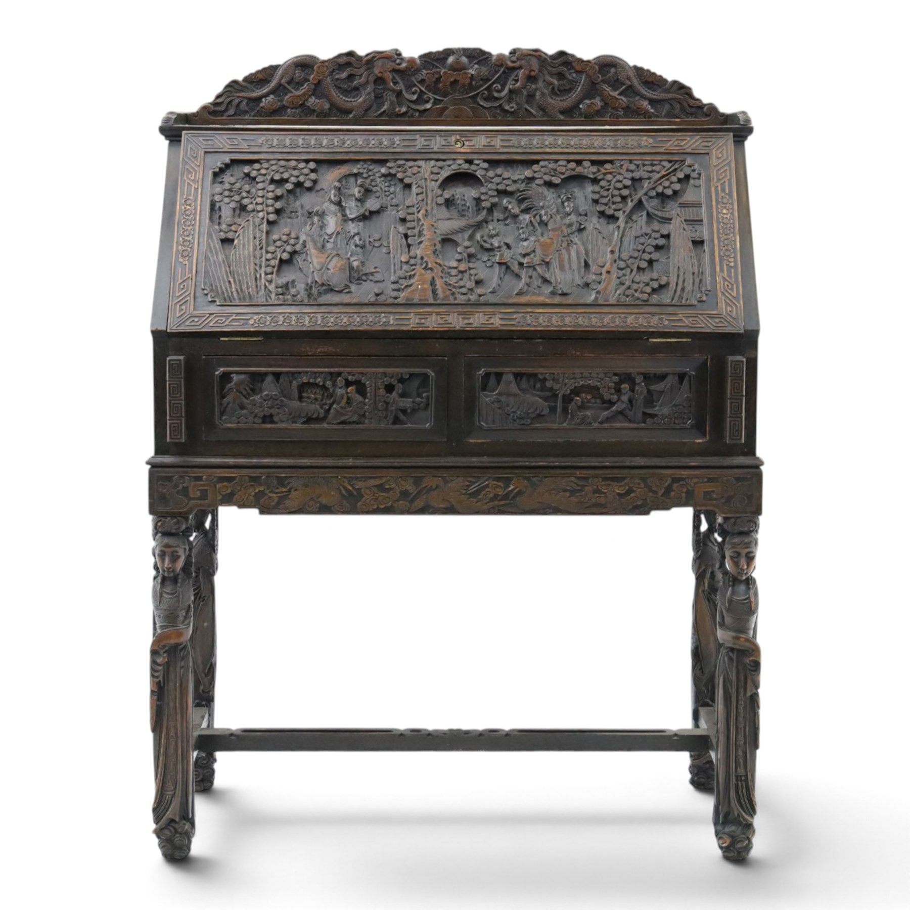 Early 20th century Chinese export carved hardwood writing bureau, the sloped fall front deeply carved with a narrative figural scene beneath pine and prunus trees, above a pair of rectangular carved panels, the shaped crest rail with entwined dragons, interior fitted with pigeonholes and a central drawer, on figural front supports with shaped stretcher