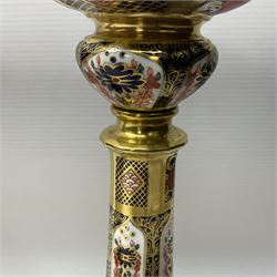 Pair of modern Royal Crown Derby Old Imari 1128 pattern candlesticks, each with shaped drip tray affixed to squat socket, upon spreading stem and canted square base with gilt dolphin edges, with printed marks beneath including Roman numeral year cypher for 2003, H26.5cm, with original boxes