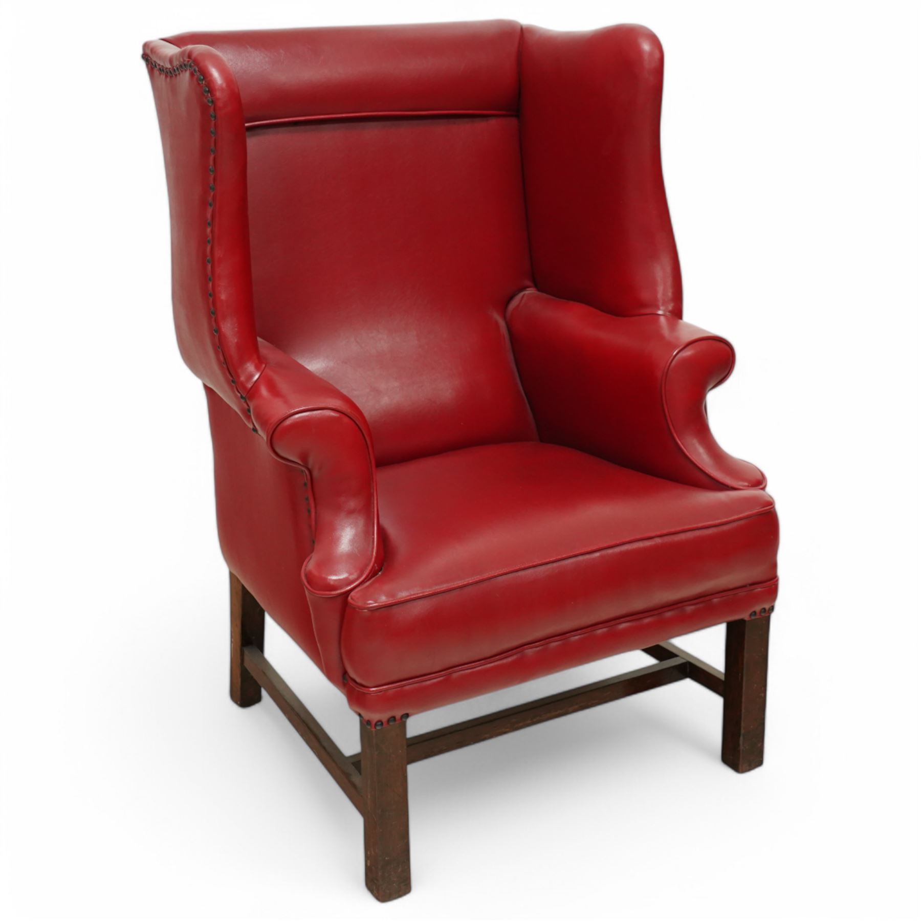 20th century Georgian design mahogany framed wingback armchair upholstered in red leather, shaped back flanked by winged sides and down-swept arms raised on squared legs 