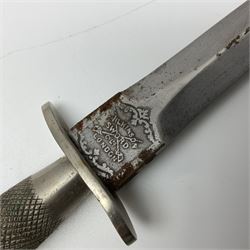 First Pattern Fairburn Sykes ''F-S'' Fighting Knife by Wilkinson Sword Ltd., the 17cm double edge steel blade with raised medial ridge to each side, each side of the ricasso with a recessed panel, one side with maker's name, the opposing side etched THE F~S FIGHTING KNIFE, with nickel plated brass recurving crossguard and diamond cut grip; in leather scabbard with metal chape