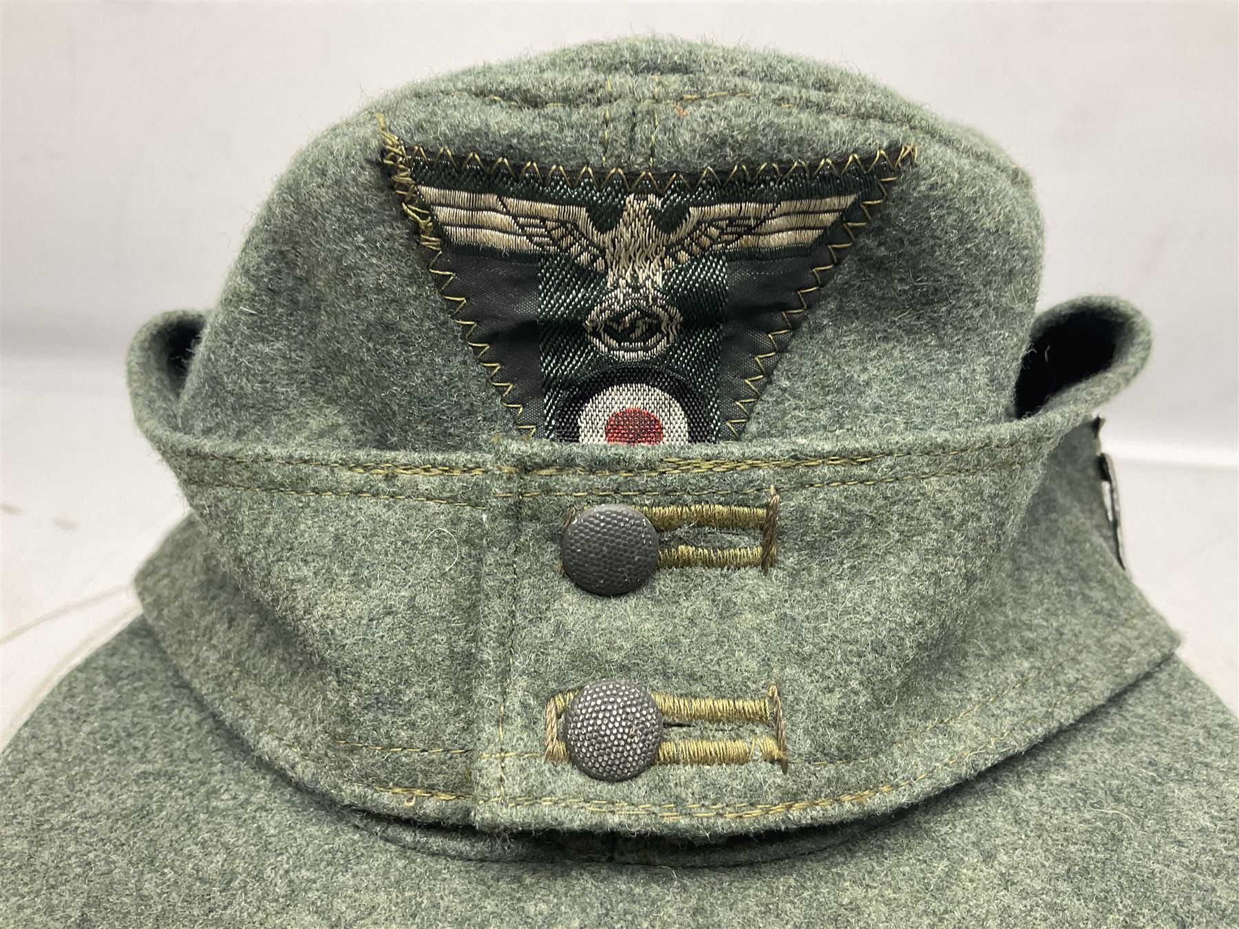 WW2 German Army M43 field cap with triangular cloth eagle and roundel badge and metal edelweiss badge for mountain troops; faintly stamped '5 VMF(?)'