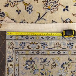 Central Persian Kashan hand-knotted carpet, ivory ground with central rosette medallion surrounded by scrolling floral vines and palmettes, field framed by a meander border flanked by multiple guard stripes, with cotton fringe end and a replaced fringe end