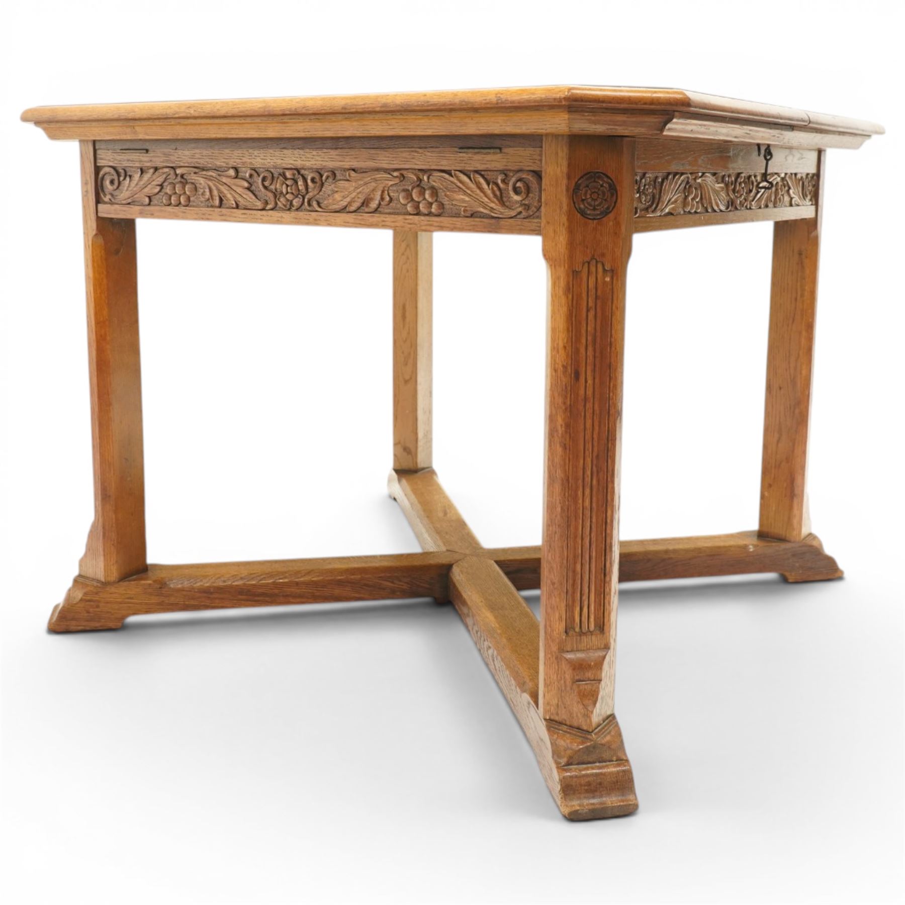 Waring & Gillow - Arts and Crafts oak draw-leaf extending dining table rectangular moulded top with chamfered corners, two additional leaves, carved frieze over fluted section supports, united by low X-shape stretchers