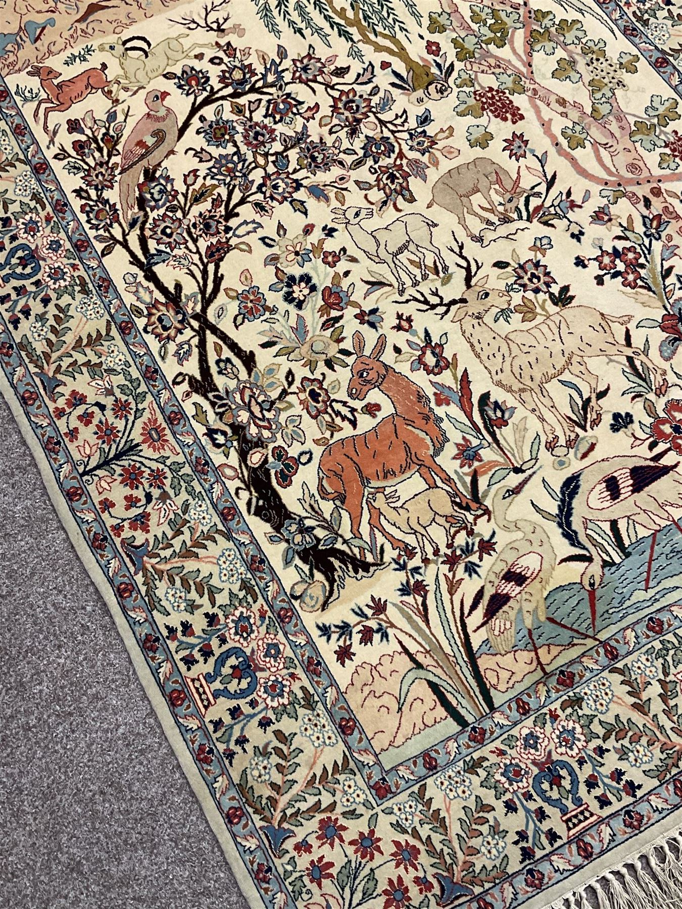 Fine Persian tree of life rug wall hanging, ivory ground field depicting landscape filled with animals, birds and flowers, the guarded border with stylised flower heads and foliage decoration, with brass hanging rail
