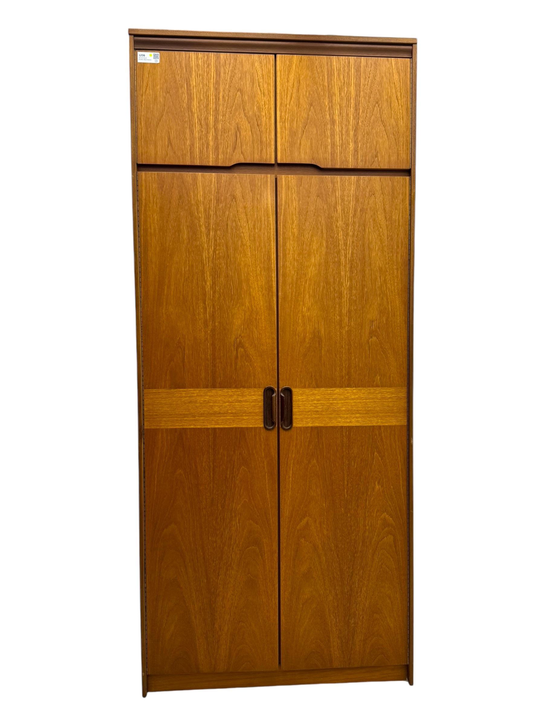 William Lawrence - mid-20th century teak double wardrobe, upper storage section over twin doors featuring recessed handles and contrasting horizontal panel, enclosing a hanging rail compartment, on plinth base with concealed castors