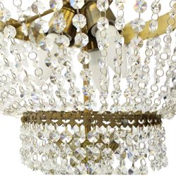 Empire design brass and crystal chandelier, the two circular brass tiers with foliate mounts, connecting the cascading crystal garlands, with prismatic drops