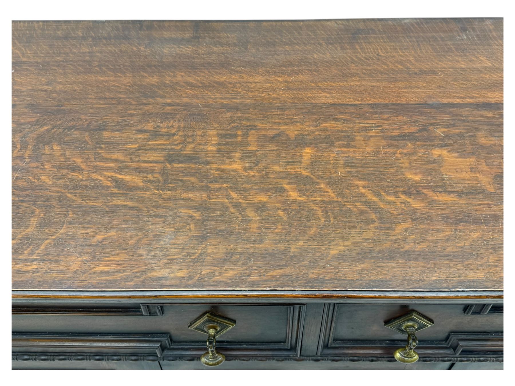 Jacobean-style oak dresser base with two frieze drawers above three cupboards with panelled and moulded decoration, fitted with drop handles, supported on bun feet, circa 1900
