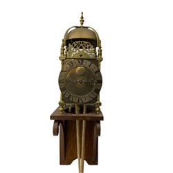 A 20th century replica of a 17th century 30-hour lantern clock with a rope driven verge escapement and countwheel striking, sounding the hours on a bell, with an engraved dial centre, silvered chapter ring and Roman numerals , half hour and quarter hour markers and a pierced and fettled steel hand, with an attached disc engraved “ Clockmaker In Scarborough Ivan Coe, Fecit,”, with engraved side doors, brass finials and dolphin fretwork, on a wooden bracket with pulley.   No weight.
Clocks similar to this were usually individually constructed by engineers working from plans of clocks designed by Claude Reeve, John Wilding, Malcolm Timings and other well-known clockmakers/engineers. 
