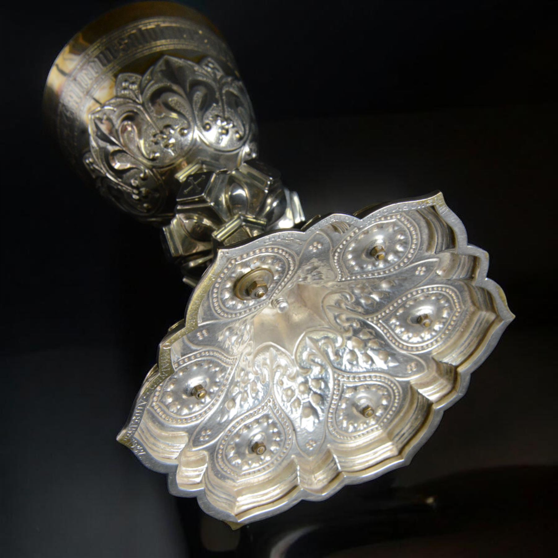 20th Century silver plated Gothic chalice, embossed throughout with fleurs de lis, foliate and bead decoration, on a knopped stem with flared and cusped foot, inset with three amethyst and two blue paste stones and applied paste and split pearl brooch, engraved beneath 'In Memory of my Mother R.I.P ... Aug 15th 1937, H23cm