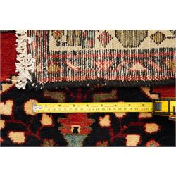 Large Persian Qashqai runner rug, the red ground decorated with navy and ivory lozenge medallions interspersed with stylised floral and geometric motifs, enclosed by an ivory flowerhead border and patterned guard stripes