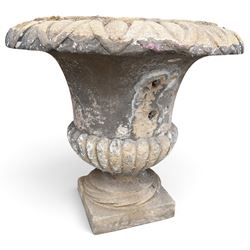Set of three 19th century weathered carved sandstone garden urns of Neoclassical campana form, the broad everted rim carved with pointed egg-and-dart motifs, above a plain waisted bowl with gadrooned underbelly, on moulded rope-twist socle and square plinth base