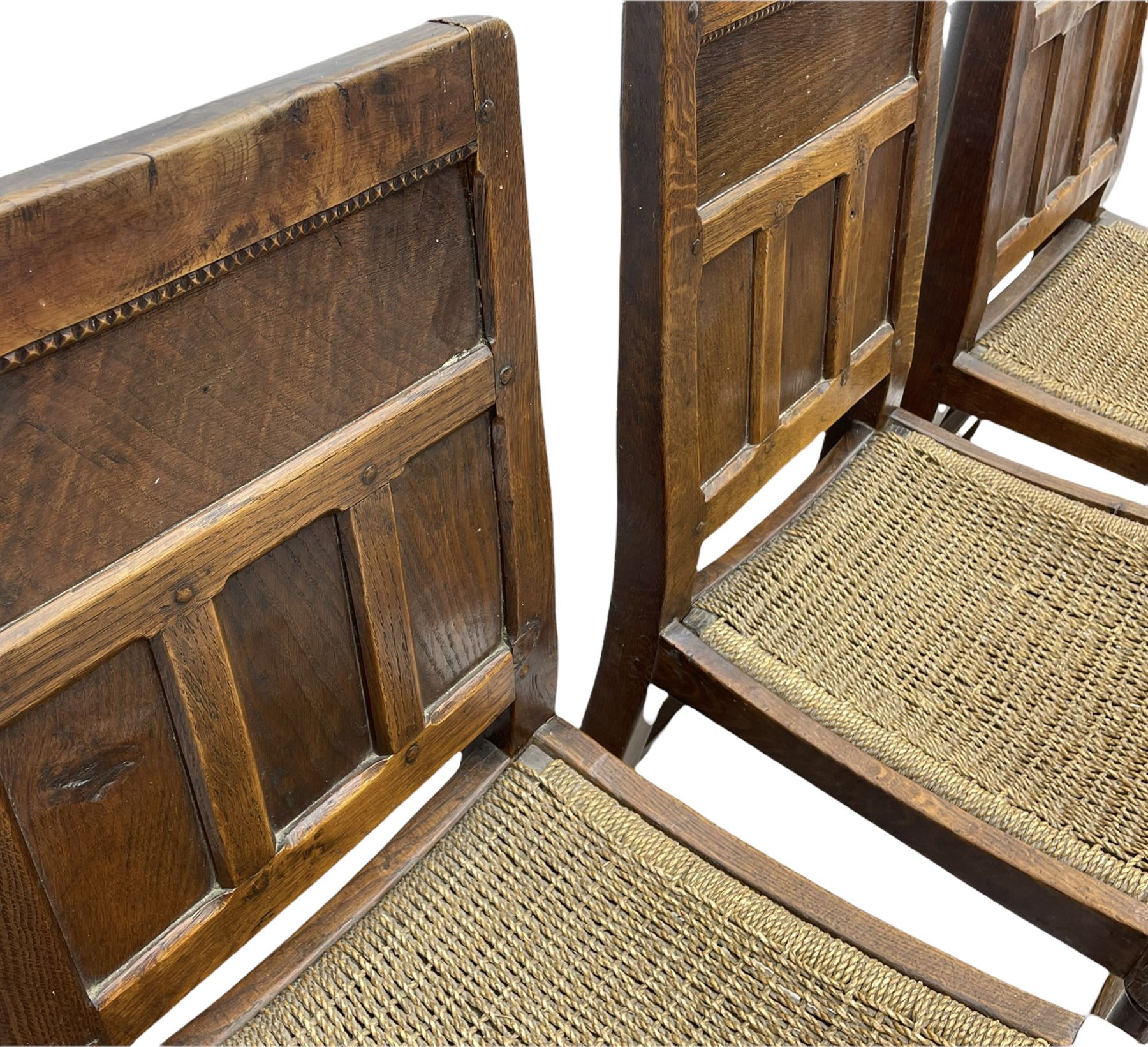'Gnomeman' set of three oak dining chairs, panelled backs over curved seat rails with drop in rope rush seats, turned front supports with collar joined by plain stretchers, two with carved seated gnome figures, painted

Provenance - This collection of early 'Gnomeman' furniture comes to us directly from the Whittaker family. The pieces were made by the vendor's father Thomas Whittaker in the 1930/40s for his own use. During this time, he lived in York and made items for himself and friends. Whittaker adopted the gnome as a signature and trademark after his move to Littlebeck, Whitby.