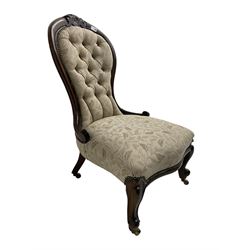 Victorian walnut spoon back nursing chair, the cresting rail carved with flower head and scrolls, upholstered in buttoned foliate patterned fabric, on cabriole front supports, brass castors