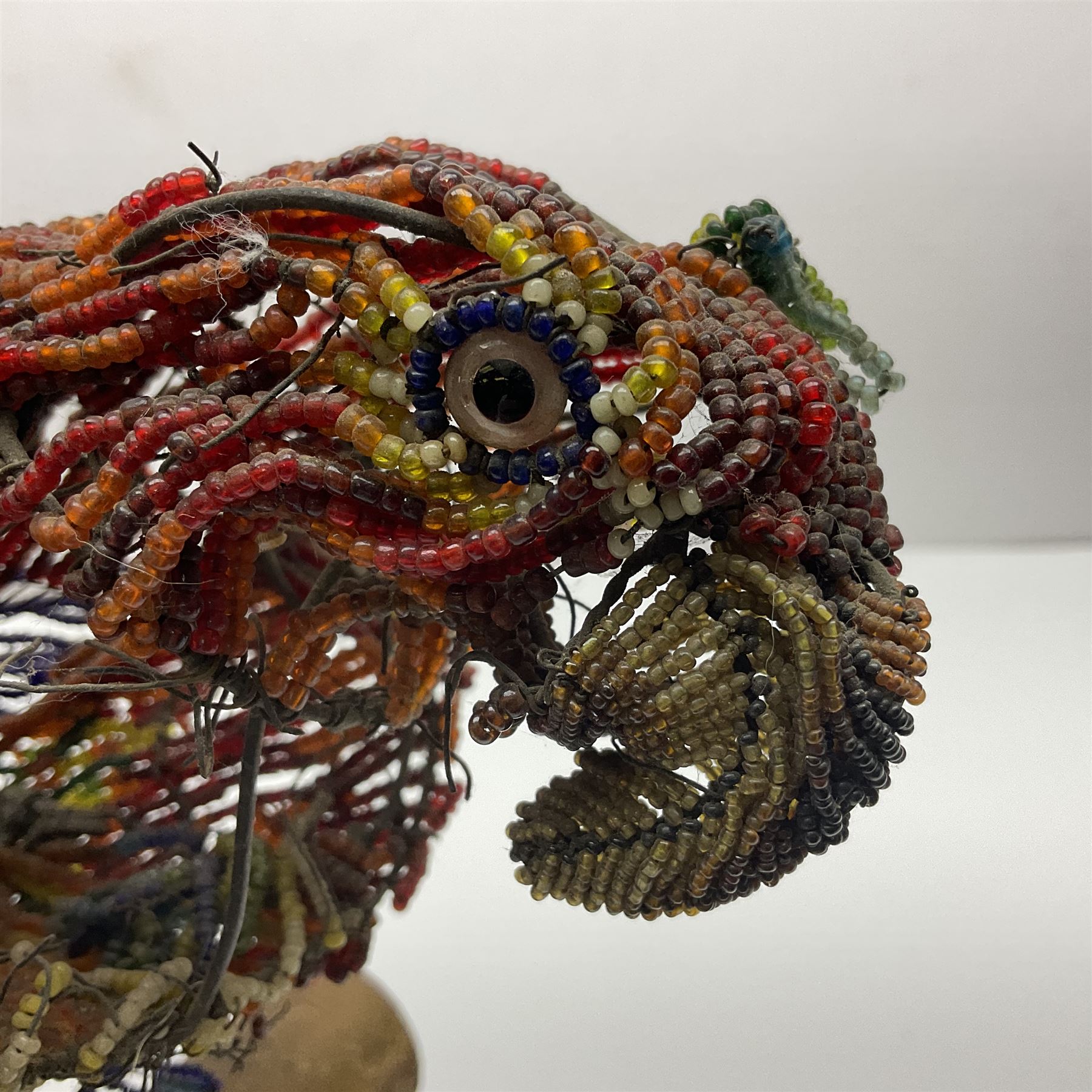 Victorian bead and wire model of a parrot, of polychrome beads, with glass eyes, on a wooden base, H24cm