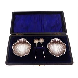 Pair of Edwardian silver open salts, each in the form of clam shells and upon three bun feet, hallmarked Faraday & Davey, Birmingham 1908, together with a pair of similar 1920s silver salt spoons, each with clam shell bowls and ball finials, hallmarked Henry Perkins & Sons, London 1922, within tooled leather velvet and silk lined fitted case