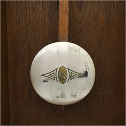 Art Deco style oak wall clock, moulded cornice above a silvered dial with Arabic numerals and geometric spandrels, glazed door with geometric bevelled glass panels enclosing a circular pendulum, on a stepped moulded base