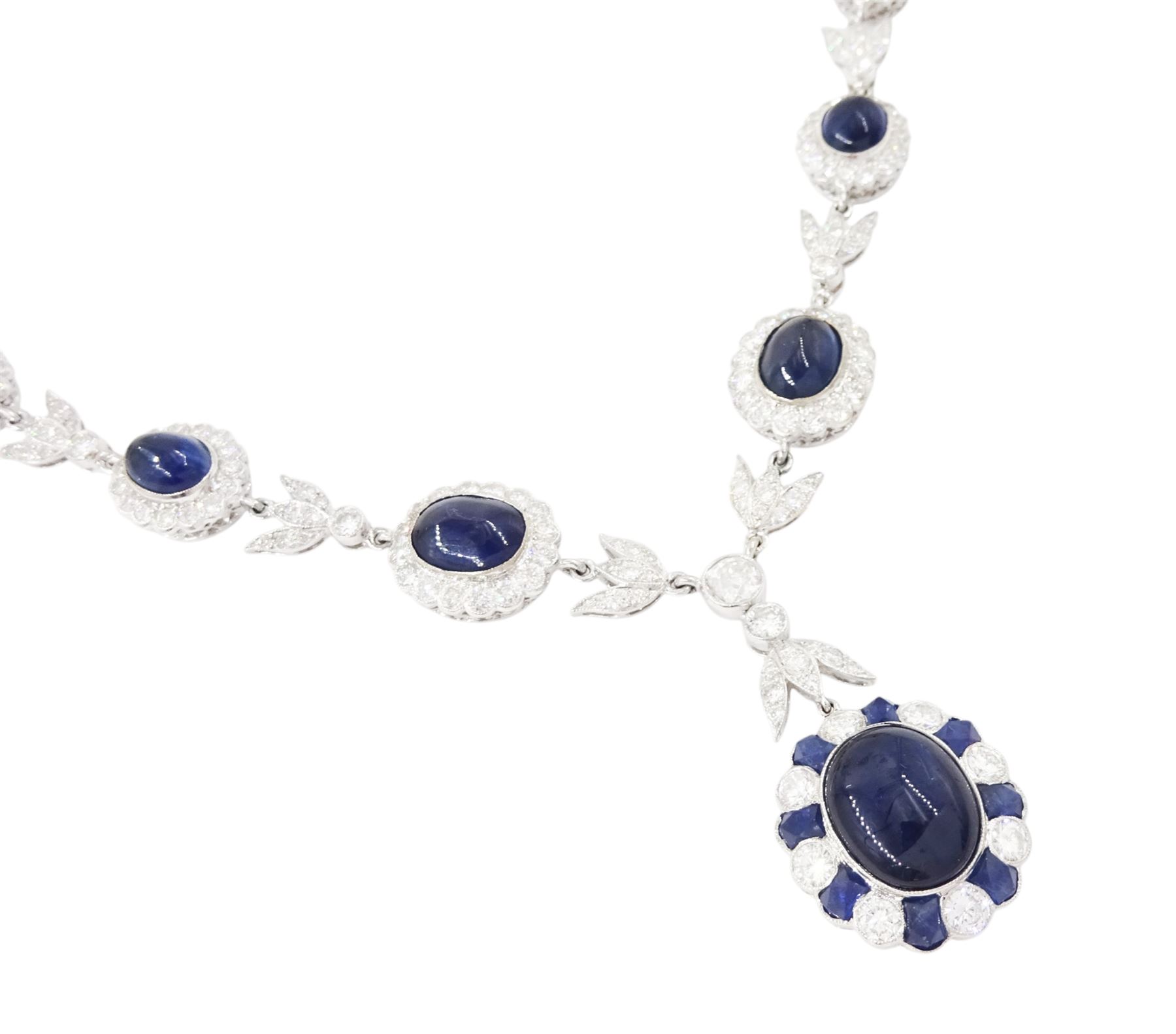 18ct white gold sapphire and diamond milgrain set necklace, oval cabochon cut sapphire surrounded by eight round brilliant cut diamonds and eight French cut sapphires, suspending from a diamond set leaf pendant, single round brilliant cut diamond and a larger old cut diamond, the chain set with six graduating cabochon cut sapphires, each surrounded by diamonds and spaced by a single diamond and a diamond set leaf, to a belcher link chain necklace, hallmarked, total sapphire weight approx 27.00 carat, total diamond weight approx 7.50 carat