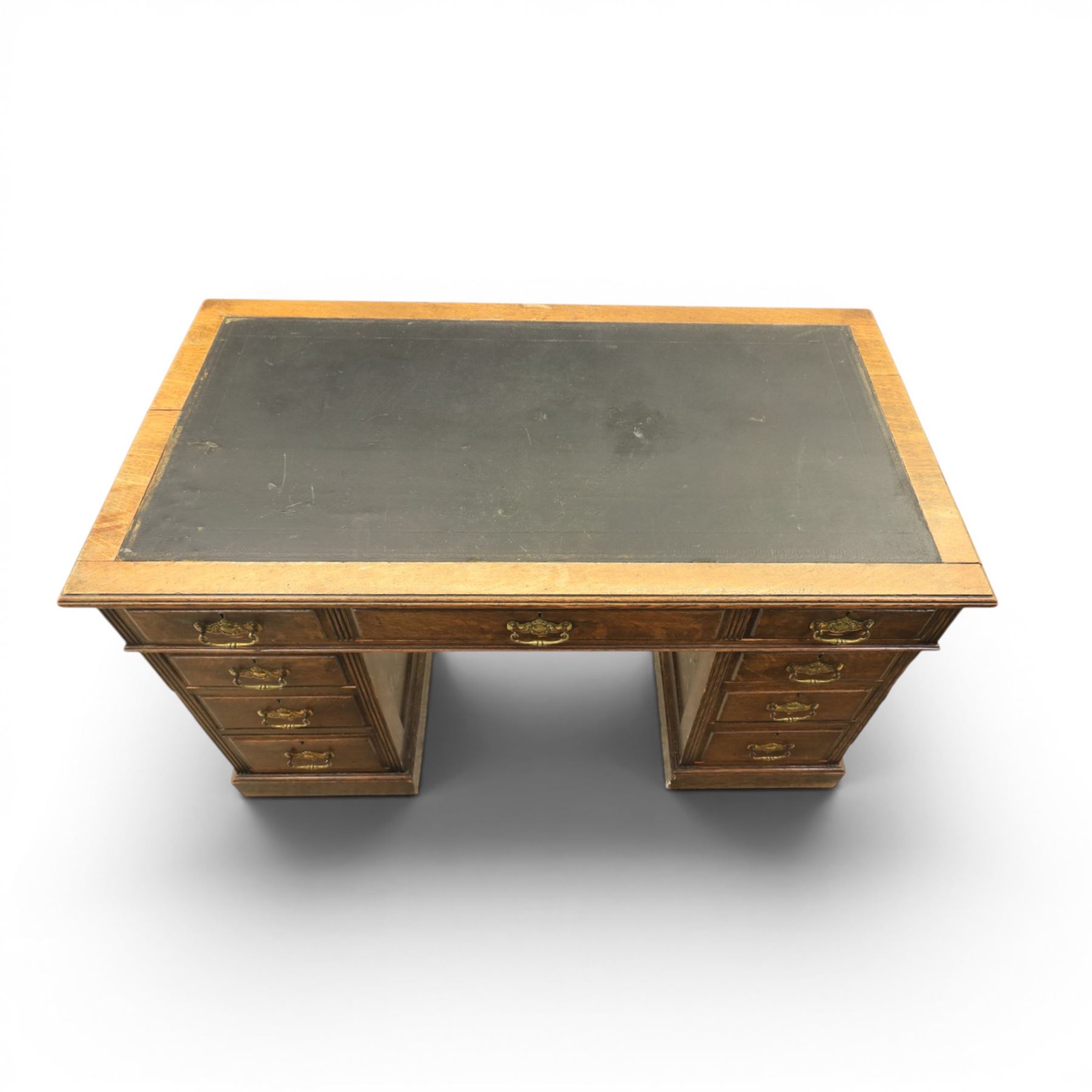 Oak twin pedestal desk with leather top, moulded rectangular top with inset black leather writing surface, nine fielded panelled drawers with brass handles, raised on a plinth base with castors