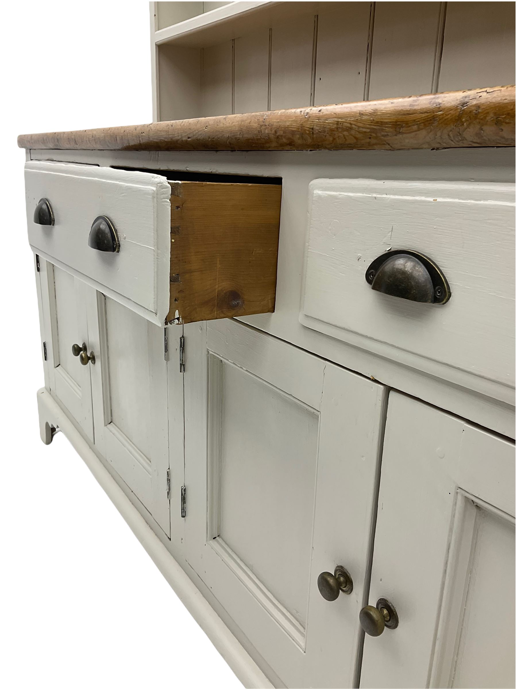 Victorian pine dresser, raised painted three heights plate rack with projecting cornice, waxed top over pained base fitted with three drawers and two double cupboards, bracket feet