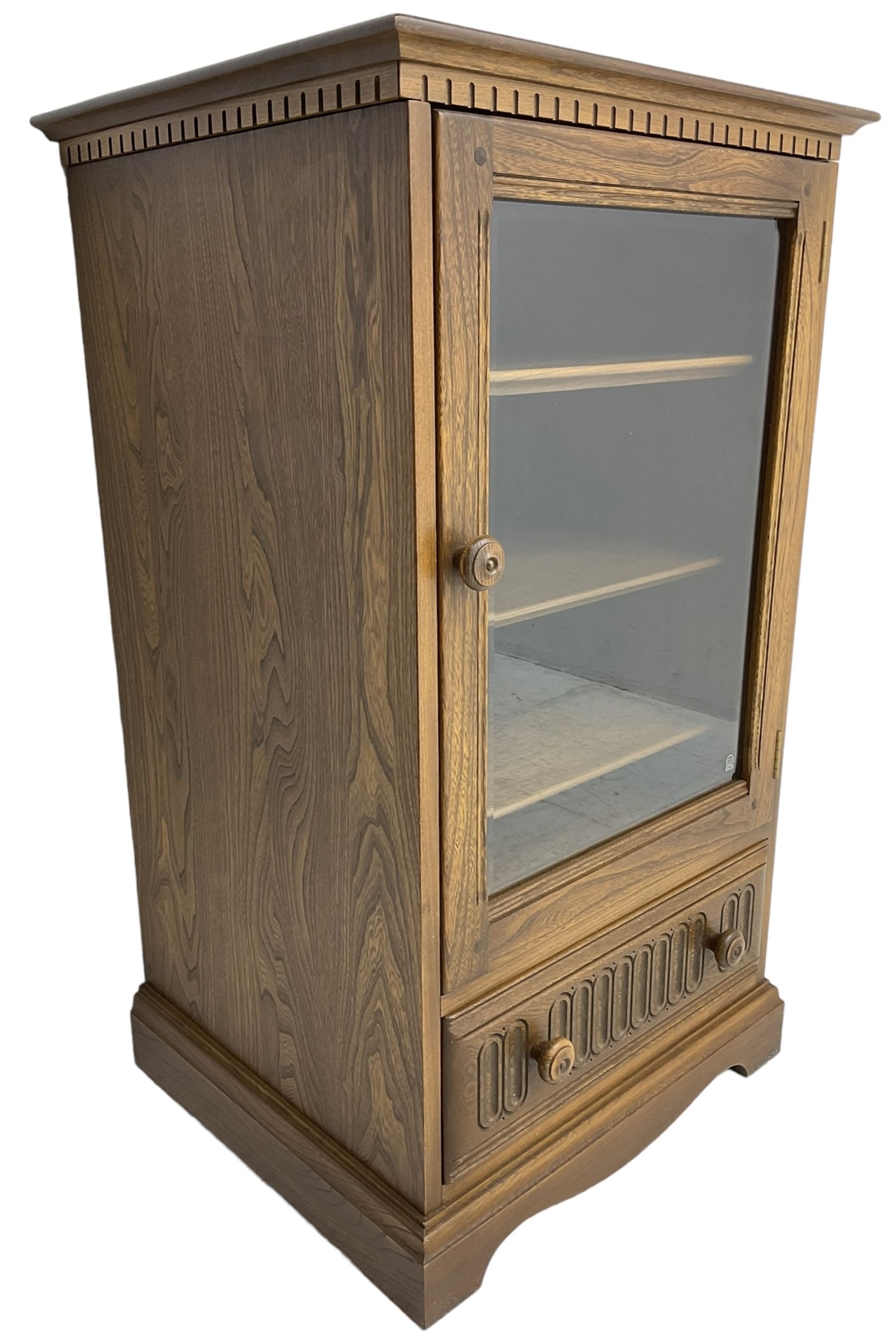 Ercol - mid-20th century dark elm 'Old Colonial' music cabinet, single glazed door enclosing three shelves, single drawer fitted to base