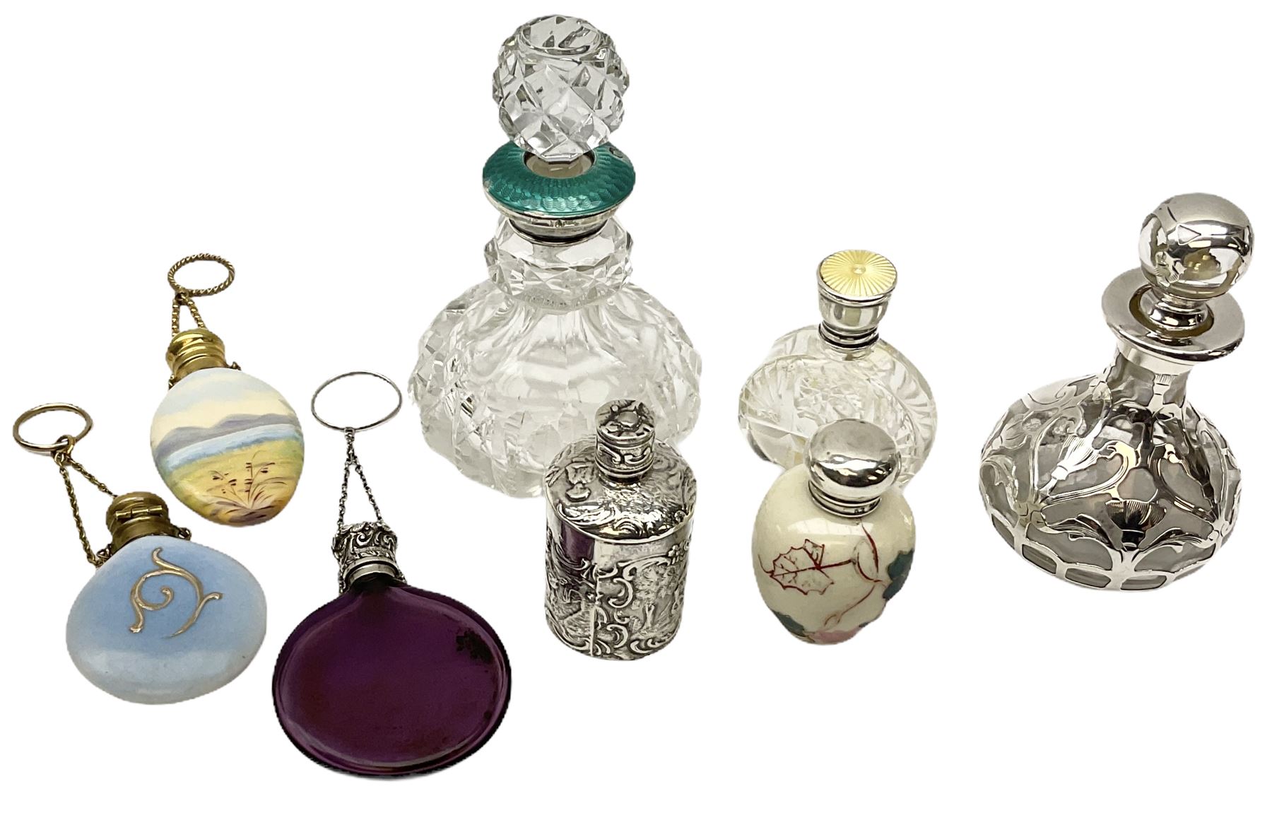Cut glass perfume bottle of bellied form, the silver mounted cover with turquoise guilloche enamel top, hallmarked Henry Perkins & Sons, London 1927, together with a cut glass perfume bottle with silver mounted and yellow guilloche enamel lid, hallmarked Albert Carter, Birmingham 1950, Continental silver perfume bottle, of barrel form with embossed figural detail, stamped 930, scent bottle of bellied form with white metal foliate pierced overlay, amethyst glass scent bottle of flask form with foliate embossed white metal cover and suspension ring and chain, and three further examples, including one of ovoid form with painted decoration and silver cover, hallmarked for Birmingham.