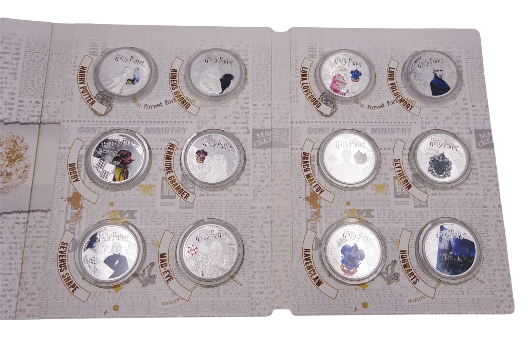 Harry Potter Wizarding World Official Coin Collection comprising twelve Samoa half dollar coins and a Harry Potter 'The Hogwarts Crest Masterpiece' medallion, cased with certificate