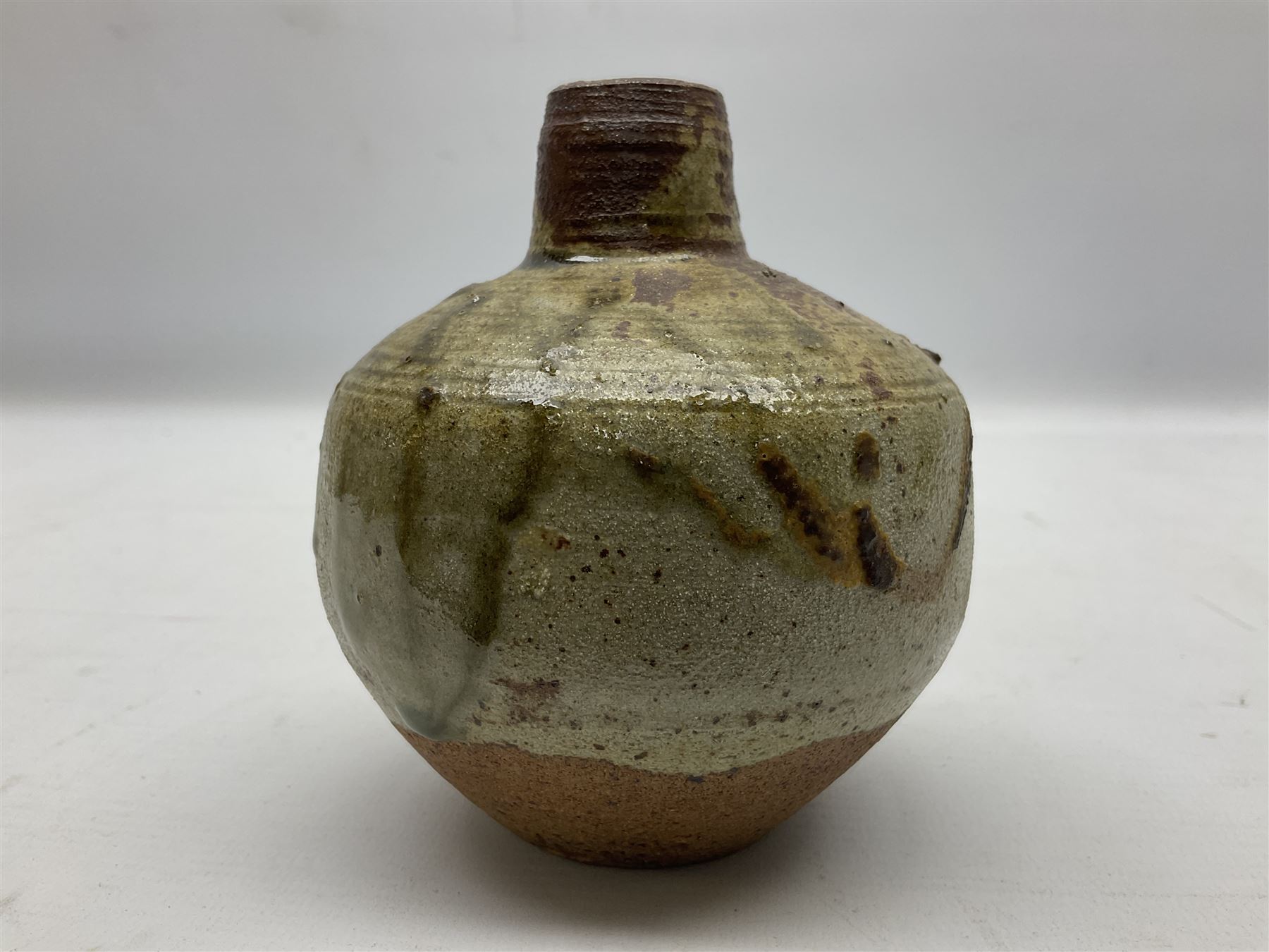 Janet Leach (American, 1918-1997) for Leach Pottery; speckled studio pottery vase of shouldered ovoid form with speckled brown decoration and trailing green and brown glaze upon beige and brown ground, with impressed J.L. monogram and Leach Pottery mark beneath, together with a Jeremy Leach blue speckled lidded circular dish with loop handle, impressed J.L, tallest H11cm