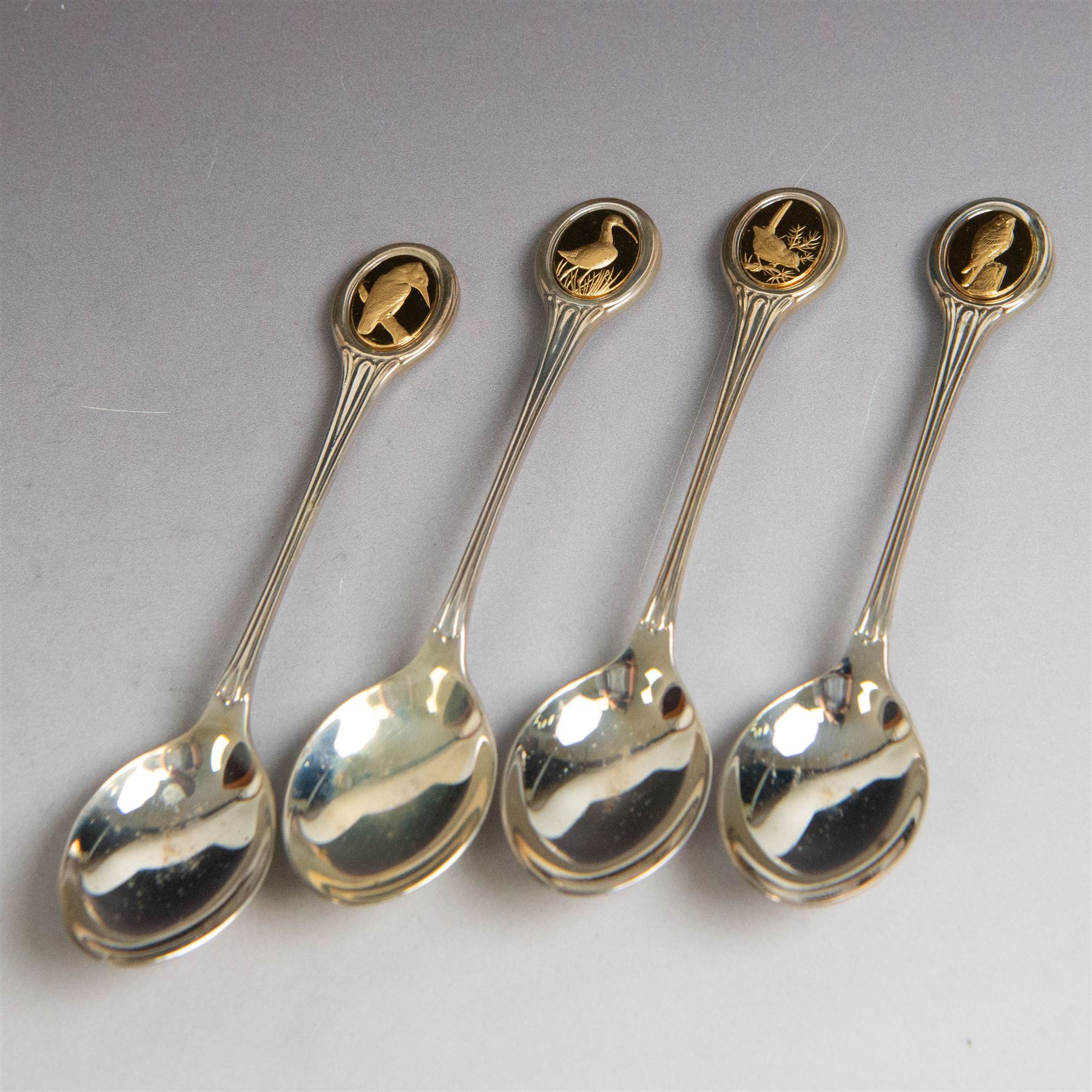 Royal Society for The Protection of Birds silver spoon collection, twelve spoons each inset with a silver-gilt bird cameo, hallmarked John Pinches Ltd, London 1975, in wooden presentation case with certificate of authenticity
