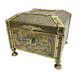 Late 19th century Damascus Cairoware Quran box, of square form with canted hinged cover, upon four circular pad feet, the brass exterior inlaid with silver and copper script and decorative detail, opening to reveal a marquetry lined interior, H15.5cm W19cm D19cm