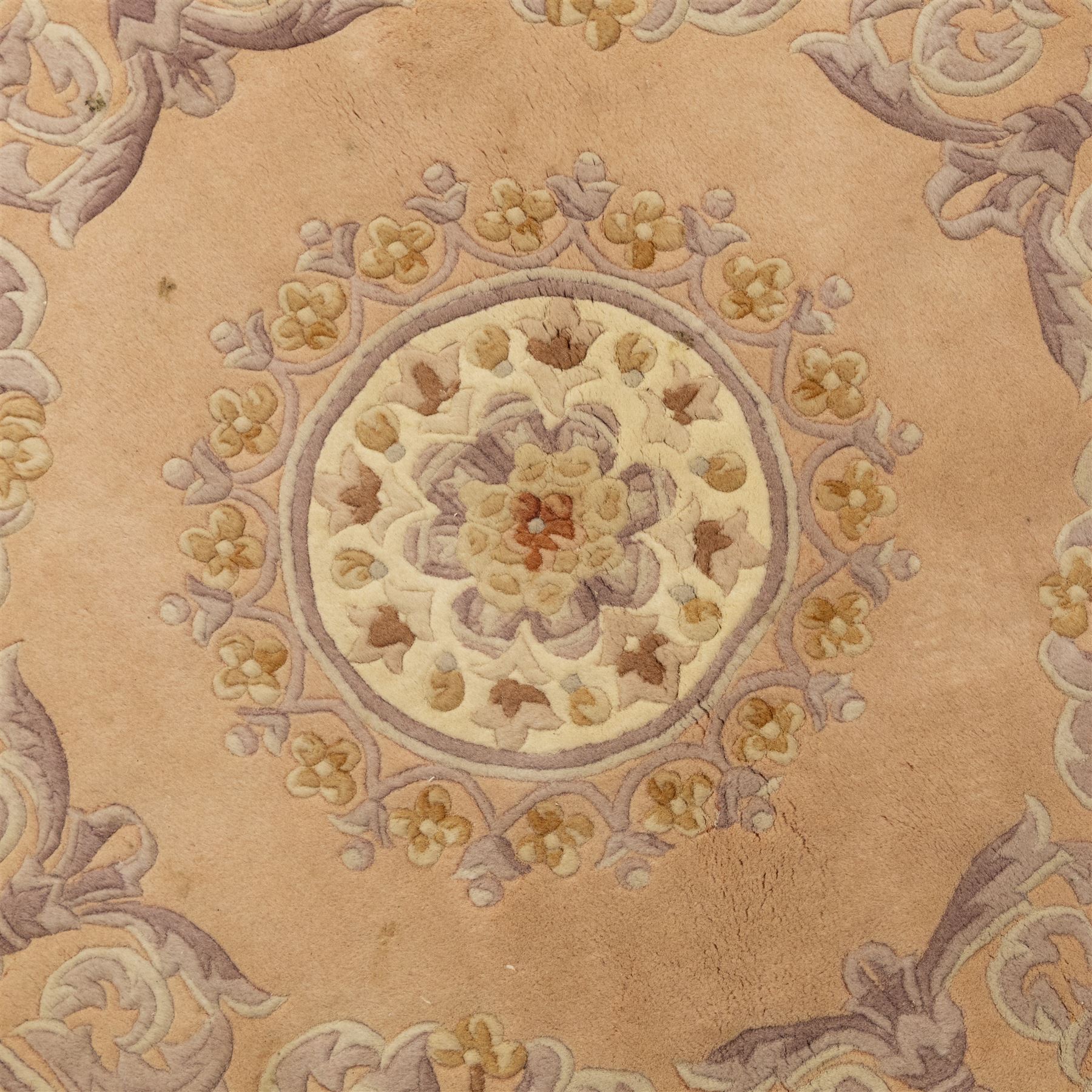Late 20th-century circular peach-toned rug, with central floral rosette medallion surrounded by scrolling floral motifs within concentric borders, with cotton fringe perimeter 