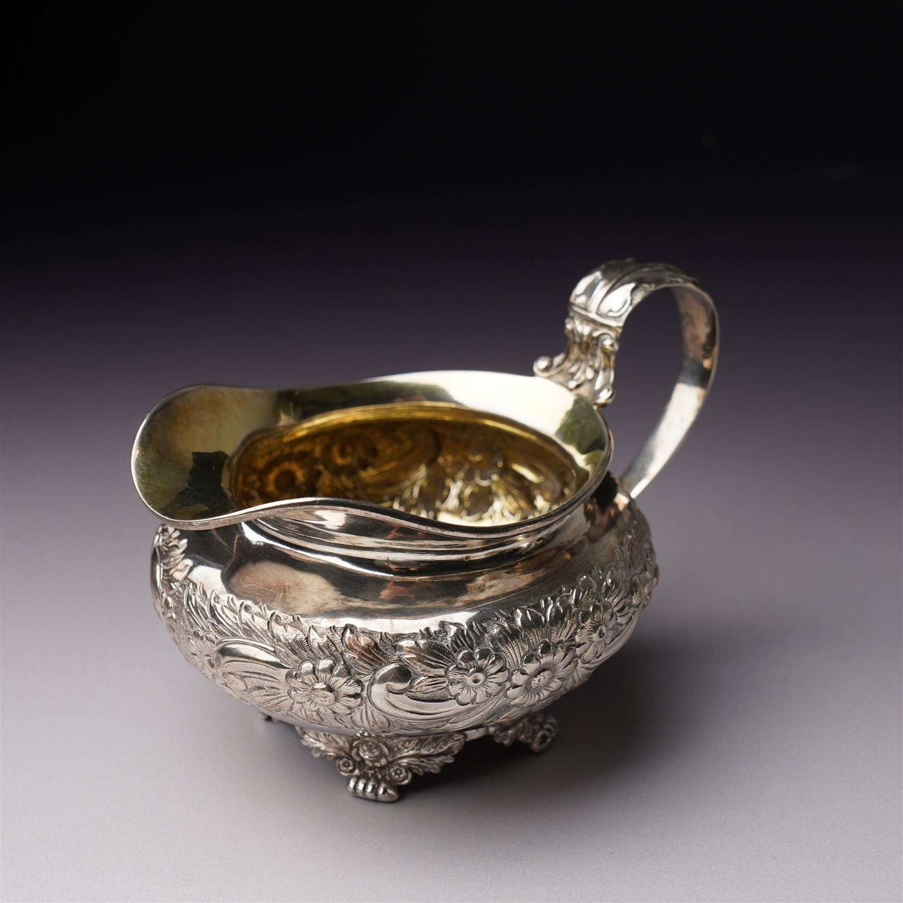 Matched three piece silver tea set comprising teapot of squat circular form London 1827,  milk jug of similar date and sugar bowl with Britannia standard marks, all with later embossed floral decoration and coat of arms, all marks rubbed