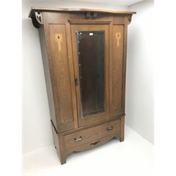 Arts and Crafts period oak wardrobe, projecting shaped cornice, single bevel edged mirrored door above drawer