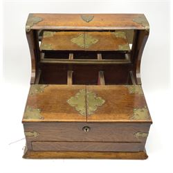 An Edwardian oak tantalus box, with brass mounts, with three recesses for decanters before a mirrored back, tand two hinged opening covers above a lower drawer, H32.5cm L36cm, D27cm. 