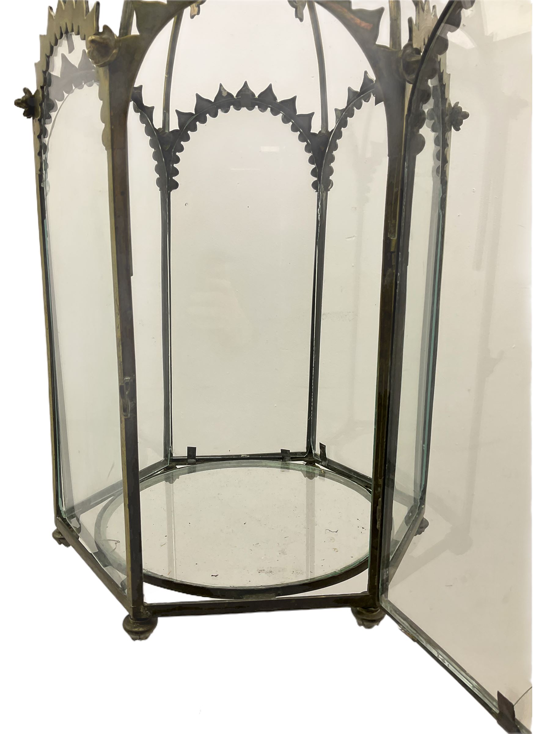 19th century brass and clear glass hexagonal hall lantern, with scrolling wire work open domed top over six arched panels, including a hinged door, the base enclosed with a circular glass panel on turned feet, H64cm