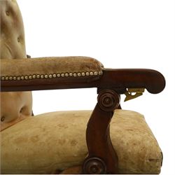 William IV mahogany gentleman's library reclining armchair, leather button upholstered and brass-studded back and seat, above leather-covered arms terminating with carved roundels and foliate scroll-carved ends, underside with brass mechanical trigger reclining lever, the apron with retractable foot rest, supported on lappet carved and turned legs with brass castors, circa 1835