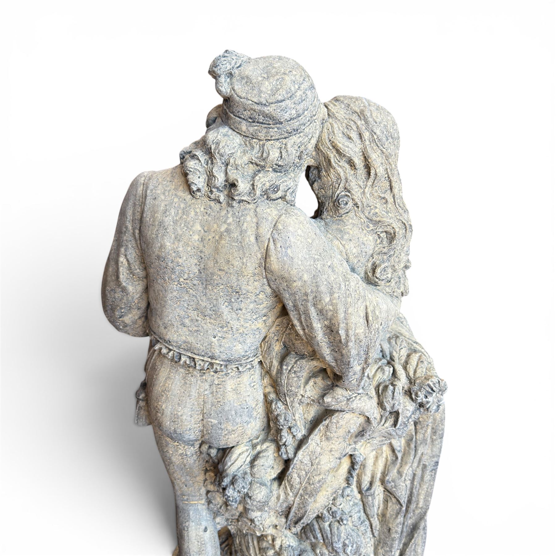 Composite garden statue group of Romeo and Juliet embracing, the couple adorned in Medieval dress standing on a naturalistic base with fallen flowers, raised on a Neoclassical fluted pedestal with Anthemion leaf motifs