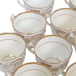 Late 19th century tea service, decorated in gilt with bands of seaweed type tendrils, thistles and cross hatch reserves upon a white glazed ground, comprising tea pot, twin handle lidded sucrier, milk jug, slop bowl, three serving plates, twelve cups and saucers and eleven side plates
